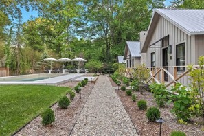 A residential property with a swimming pool, outdoor seating, and a gravel pathway.