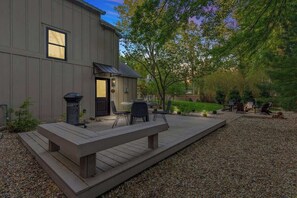 A modern house with a deck, outdoor seating, and a grill.