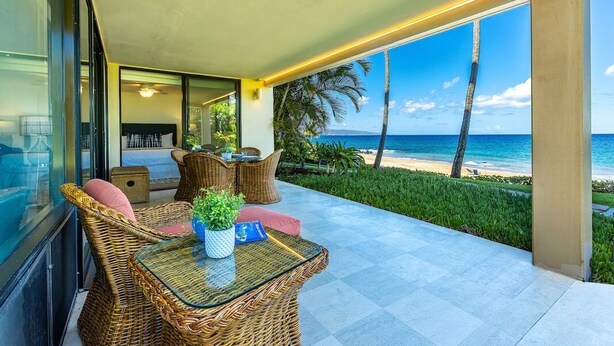 A balcony with wicker furniture, a glass table, and a view of the ocean. - Polo Beach Club 106 2 Bedroom Condo (Kihei)