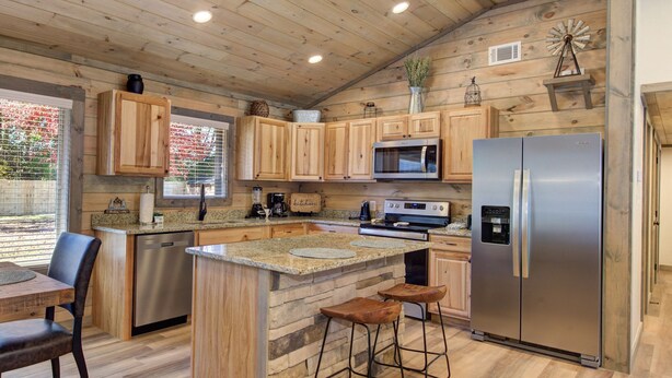 A kitchen with wooden cabinets, a granite countertop, a stainless steel refrigerator, and a stone island with bar stools. - Cute 3 Bedroom 2 Bath and ONLY 5 Minutes to Pigeon Forge (Pigeon Forge)