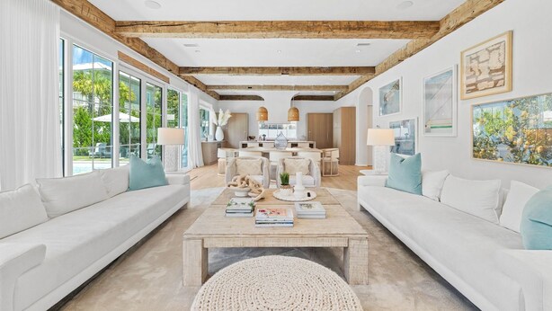 A spacious living room with a large coffee table, white sofas, and a wooden ceiling.