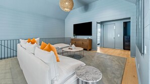 A modern living room with a white sofa, a round coffee table, and a unique spherical light fixture.