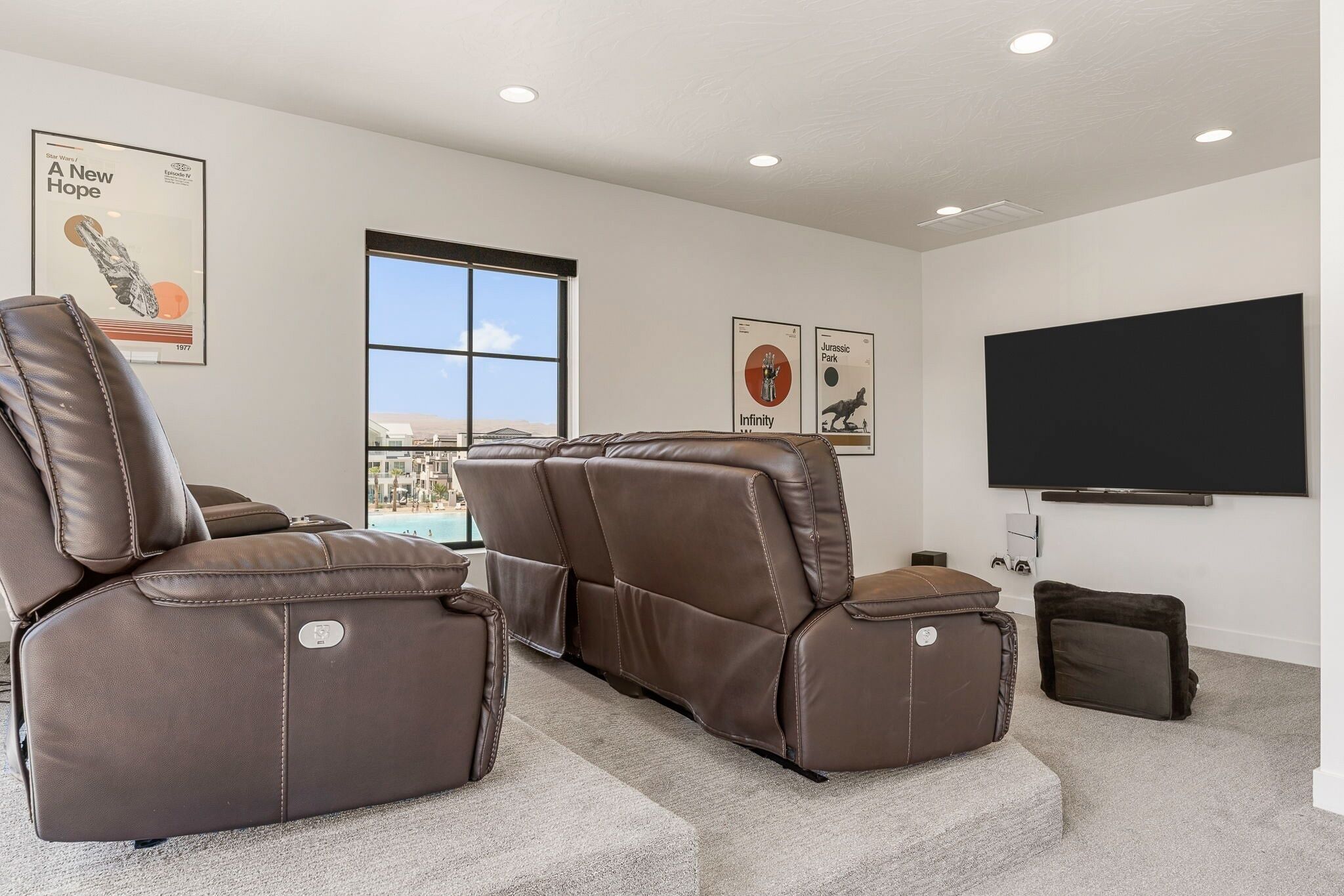 A home theater with reclining chairs, a large flat-screen TV, and posters on the wall.