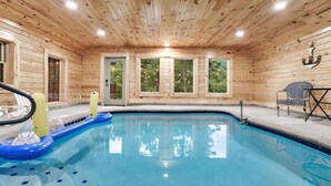 En træhytte med swimmingpool, jacuzzi og et bord med stole.