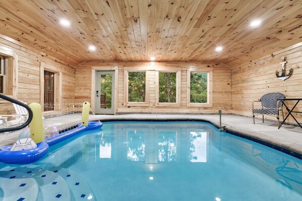 A wooden cabin with a swimming pool, a hot tub, and a table with chairs. - Brand New! Indoor heated pool, Mountain View’s! (Sevierville)