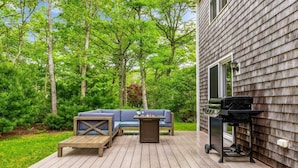 Eine Terrasse mit Grill, einer blauen Couch und einem kleinen Tisch.