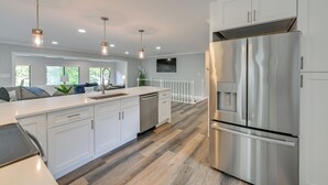 A modern kitchen with white cabinetry, stainless steel appliances, and a wooden floor.