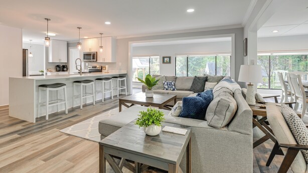 A spacious living area with a kitchen, a large sofa set, and a dining table.