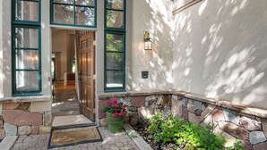 A house entrance with a stone wall, a potted plant with flowers, and a door leading inside. - Single family home on Beaver Creek golf course with lots of upgrades!! (Beaver Creek)