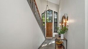 A hallway with a wooden door, a staircase, and a wall-mounted light fixture. - Single family home on Beaver Creek golf course with lots of upgrades!! (Beaver Creek)
