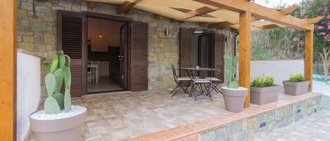 A patio area with a stone wall, wooden pergola, and potted plants.