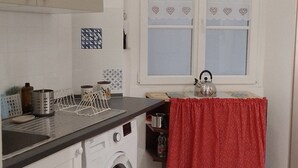 A compact kitchen with a washing machine, a sink, and a window with a patterned curtain. - Ca' Sanlò2 confortable and near to Acquario of Genoa (Genova)