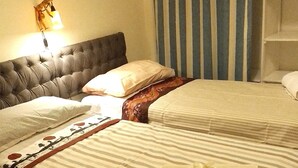 A hotel room with two beds, striped bedding, a tufted headboard, a wall-mounted lamp, and a striped curtain. - Ca' Sanlò2 confortable and near to Acquario of Genoa (Genova)