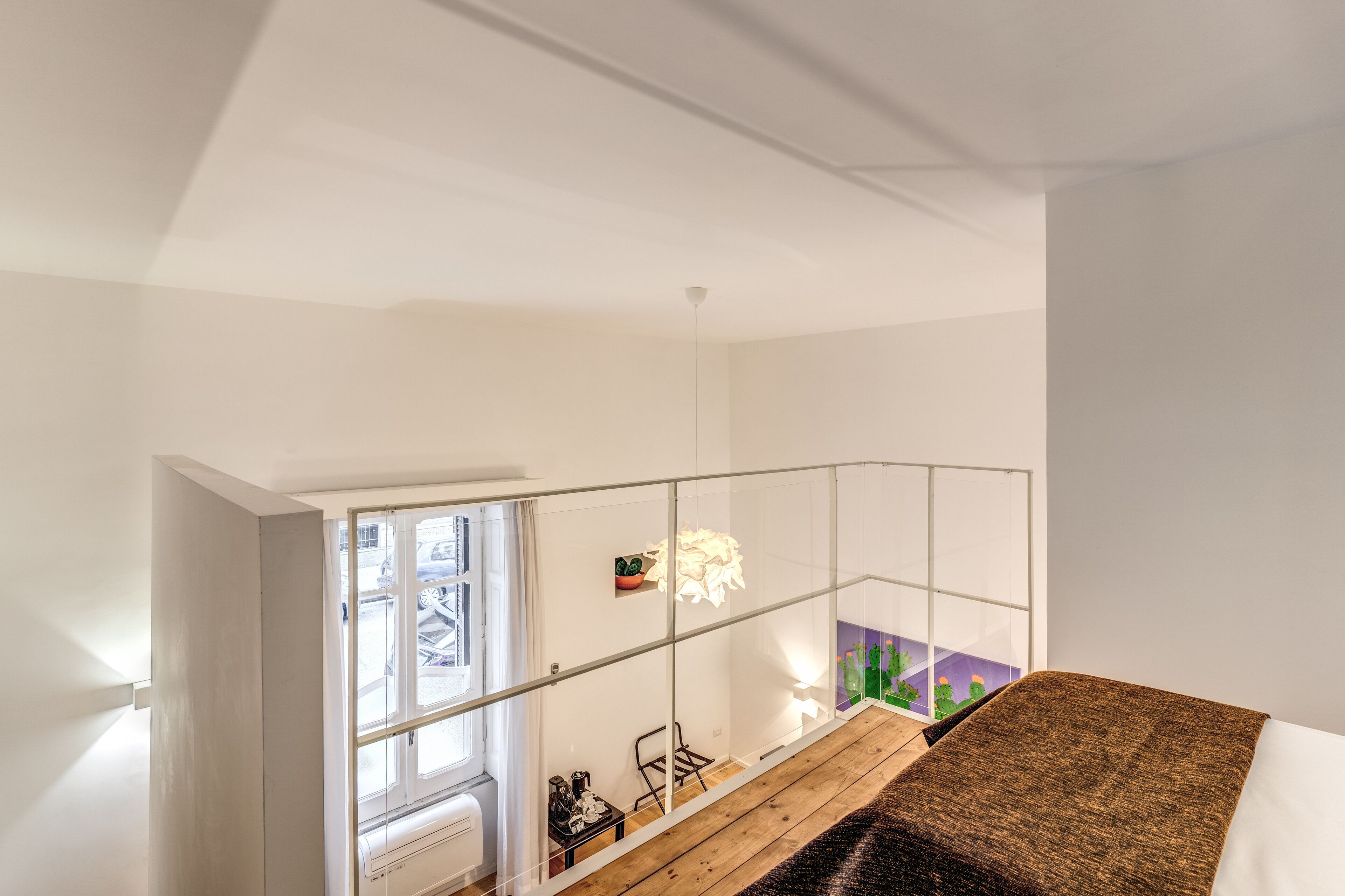 A modern interior with a wooden floor, a glass railing, and a view of the street outside.
