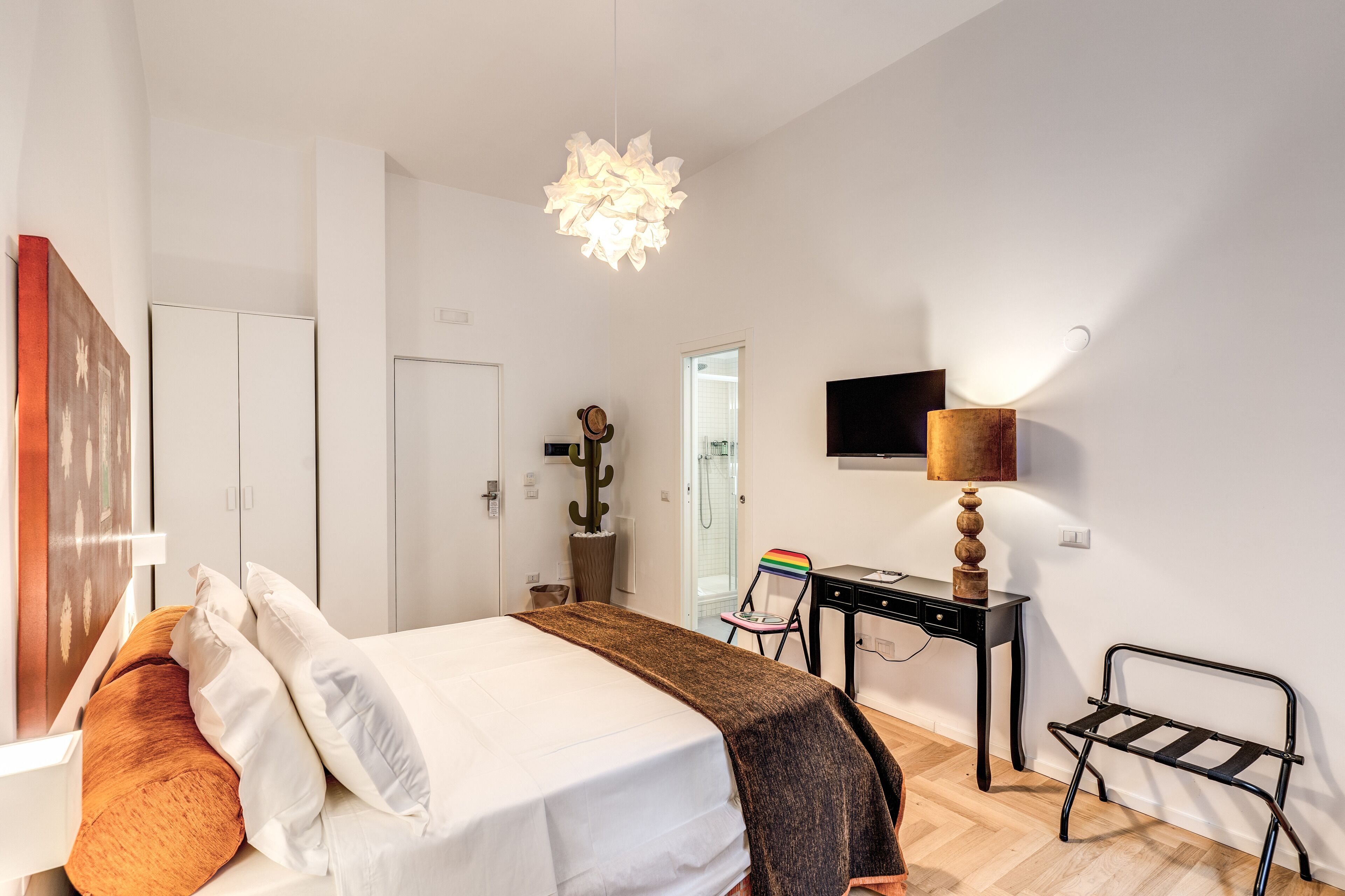 A modern bedroom with a bed, bedside table, lamp, and a chair.