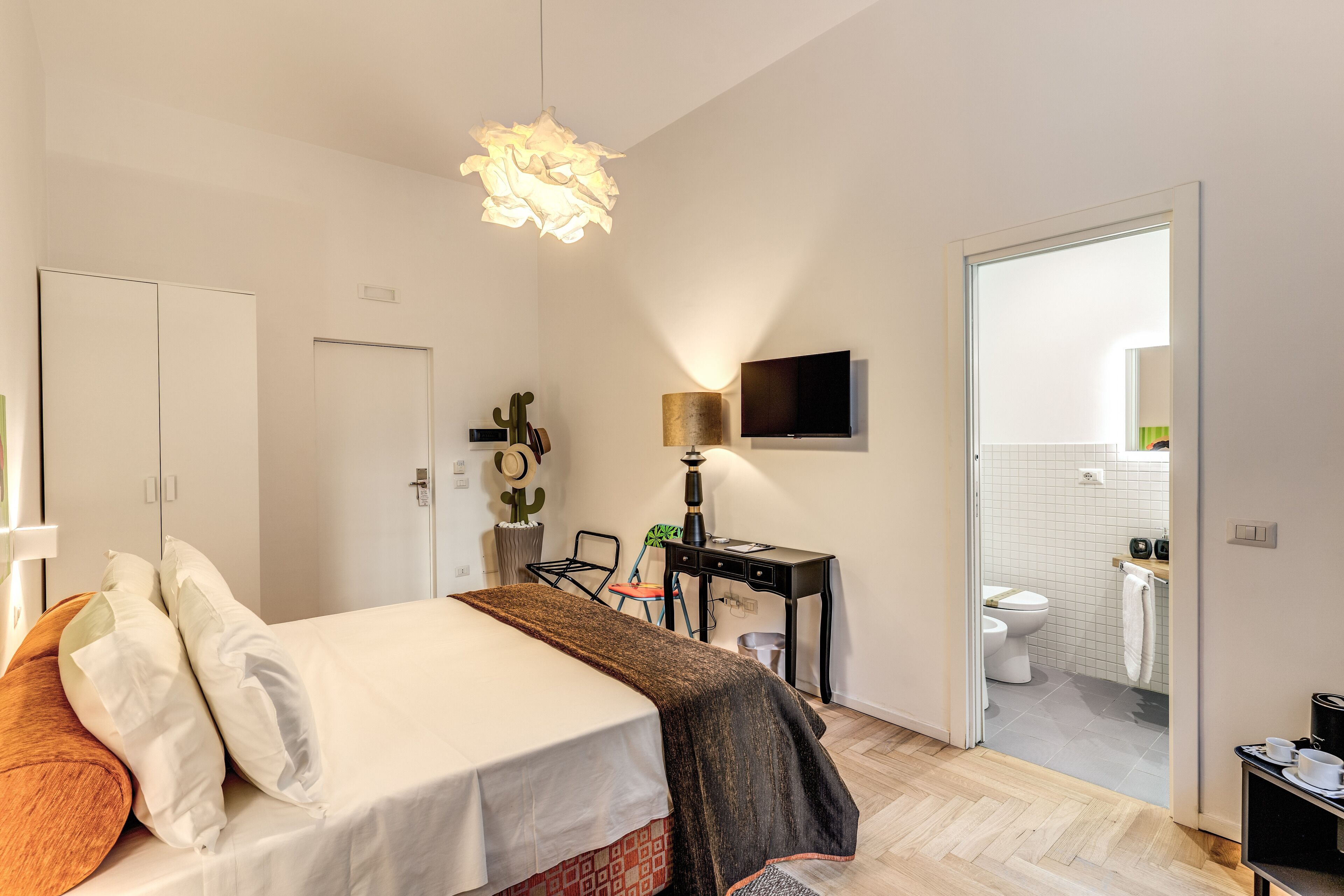 A bedroom with a bed, bedside table, lamp, and a view into the bathroom.