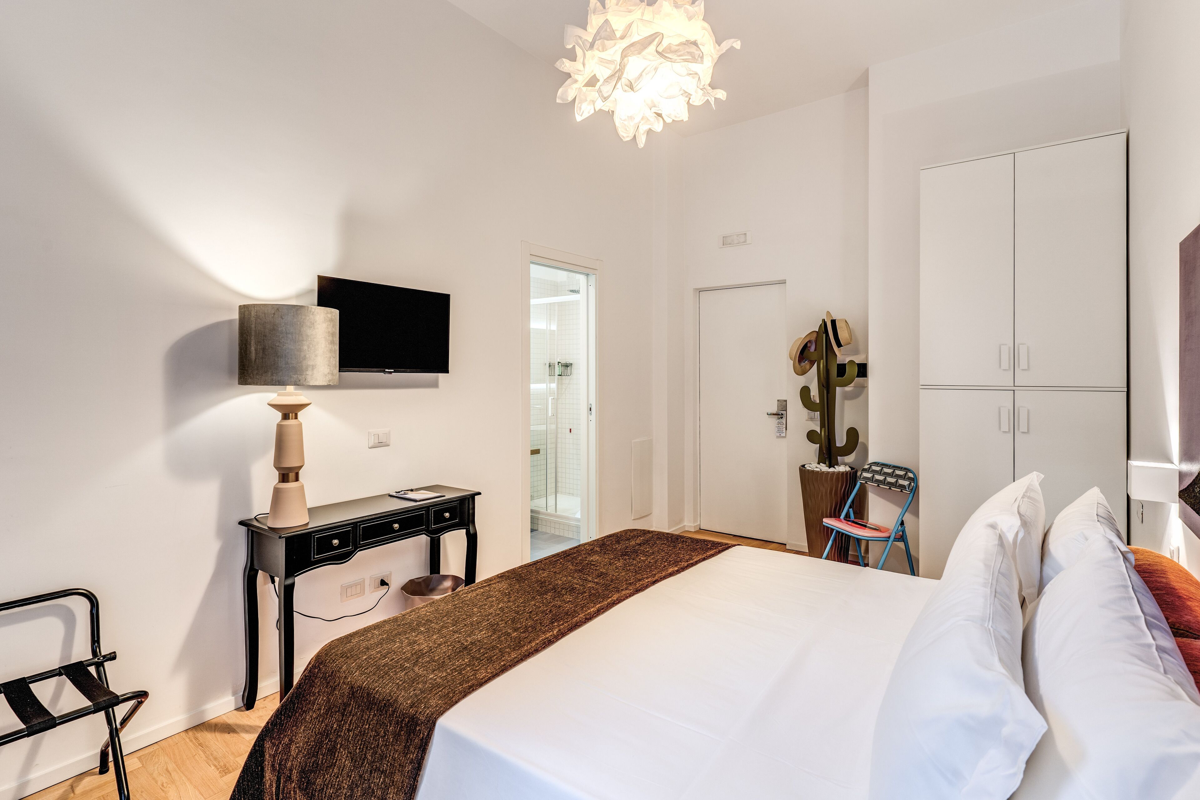 A modern bedroom with a bed, a desk, a chair, a TV, and a wardrobe.