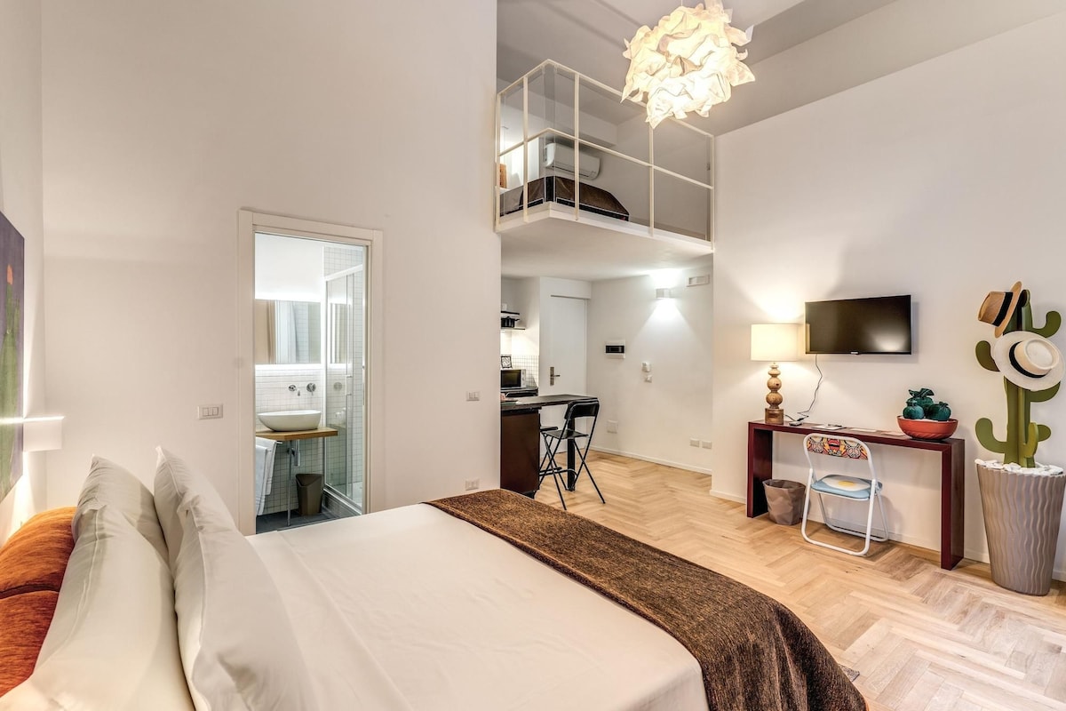 Une chambre moderne équipée d’un lit, d’un bureau, d’une chaise, d’une télévision et d’un balcon.