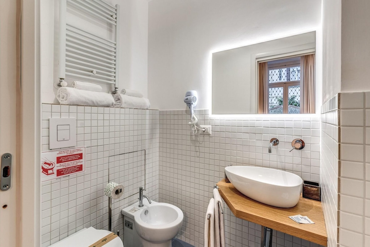Une salle de bain équipée de toilettes, d’un bidet, d’un lavabo, d’un porte-serviettes et d’un sèche-cheveux.