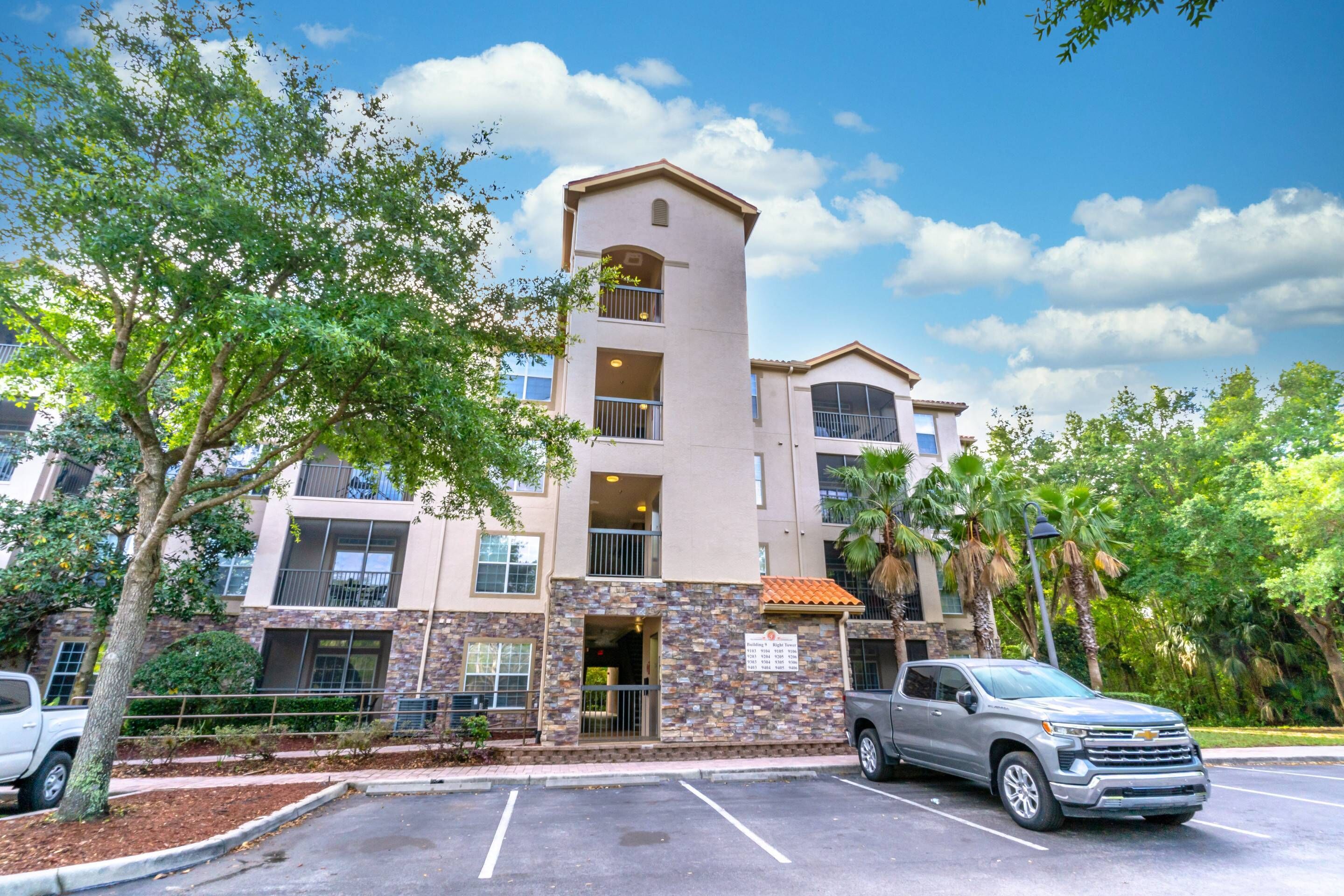 A multi-story building with a central tower, parking lot, and surrounding greenery.