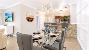 A modern dining area with a glass table, leather chairs, and a chandelier. - 1301 Flamingo Cove at Tuscana (Davenport)