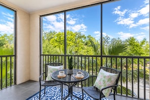 A balcony with a round table, two chairs, and two cups of coffee. - 1301 Flamingo Cove at Tuscana (Davenport)
