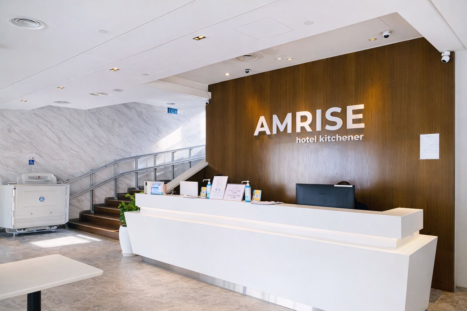 A reception desk with a wooden panel wall and the AMRISE hotel kitchener's name.