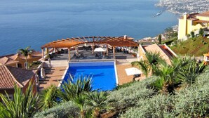 Un espace piscine agrémenté d’une pergola, de chaises longues et offrant une vue sur la mer.