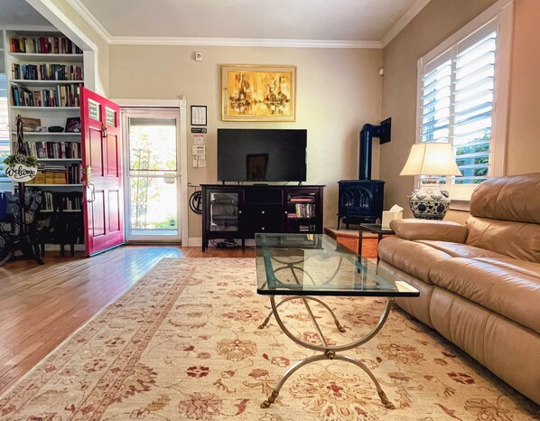 A living room with a glass coffee table, a sofa, a television, a bookshelf, and a fireplace. - A Spacious and Elegant 3BR Californian Retreat (Jackson)