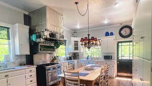 Une cuisine moderne avec des meubles blancs, un îlot central et un coin repas doté de chaises en bois.