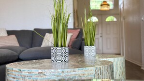 A living room with a grey sofa, two patterned vases with green plants on a mosaic table, and a door in the background. - Convenient to Restaurants, Pool, Golf Views (Davenport)