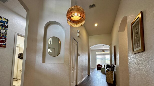 A hallway with wooden flooring, white walls, a mirror, and a hanging light fixture. - Convenient to Restaurants, Pool, Golf Views (Davenport)
