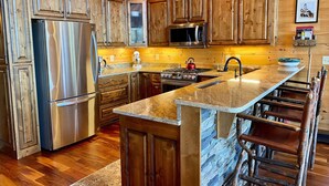 A kitchen with wooden cabinets, stainless steel appliances, a granite countertop, and a stone backsplash. - Stunning Views From Lodge, and With hot Tub! (Blue Ridge)