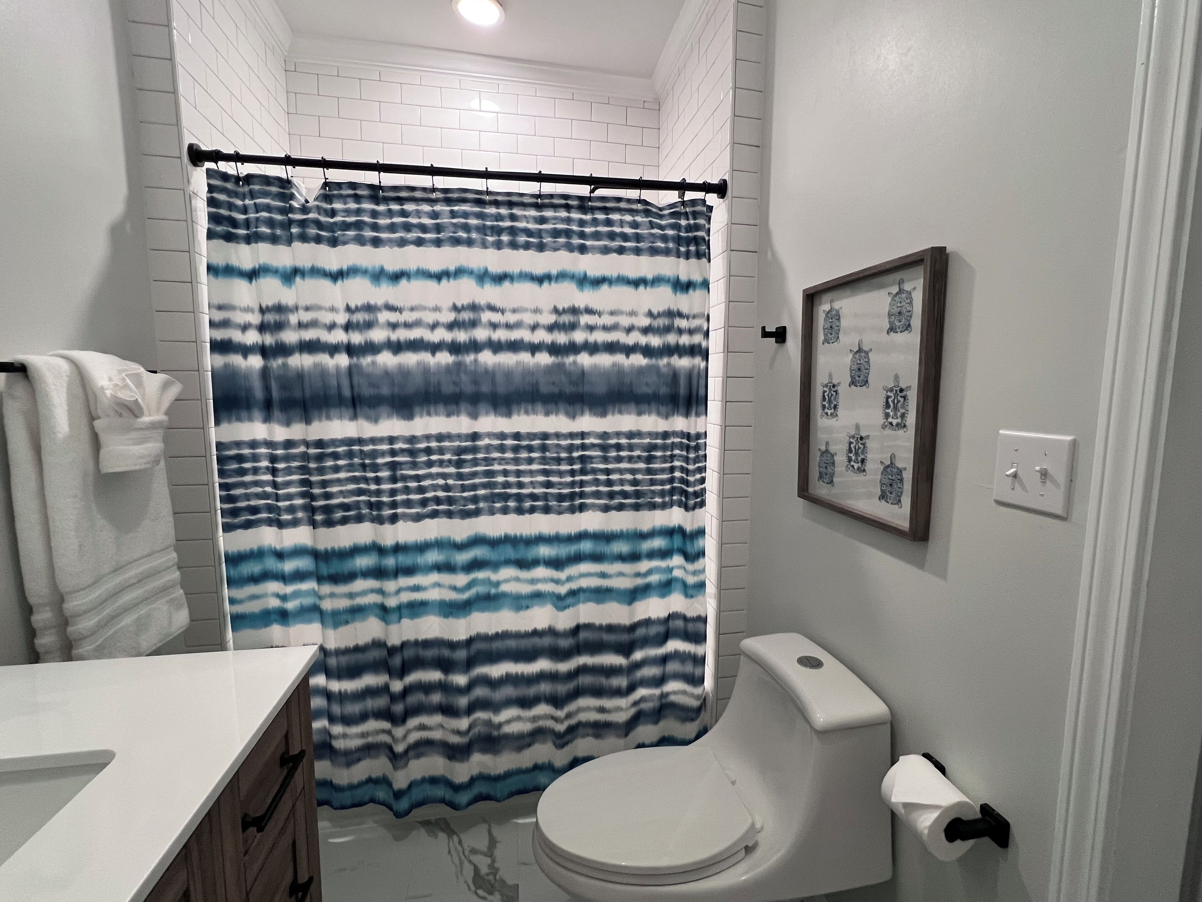 A bathroom with a white toilet, a white sink, and a blue and white striped shower curtain.