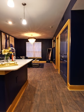 A modern kitchen with a central island, wooden flooring, and a chandelier. - Live Like ROYALTY in Buckhead This unique place has a style all of its own. (Atlanta)