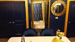 A room with a dark blue door, a round mirror with a gold frame, and a table with two chairs. - Live Like ROYALTY in Buckhead This unique place has a style all of its own. (Atlanta)