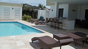Une piscine avec des chaises longues et un espace patio.