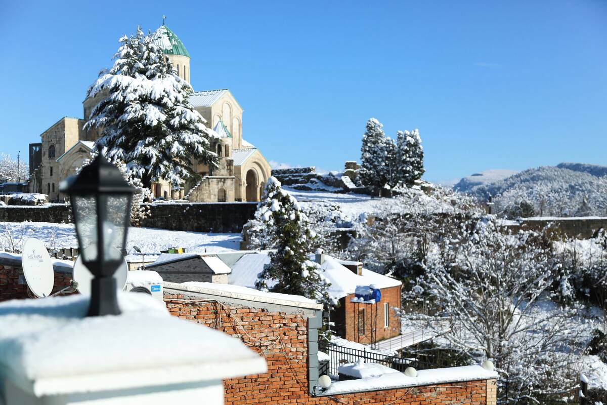 A snow-covered landscape with a church and brick buildings.