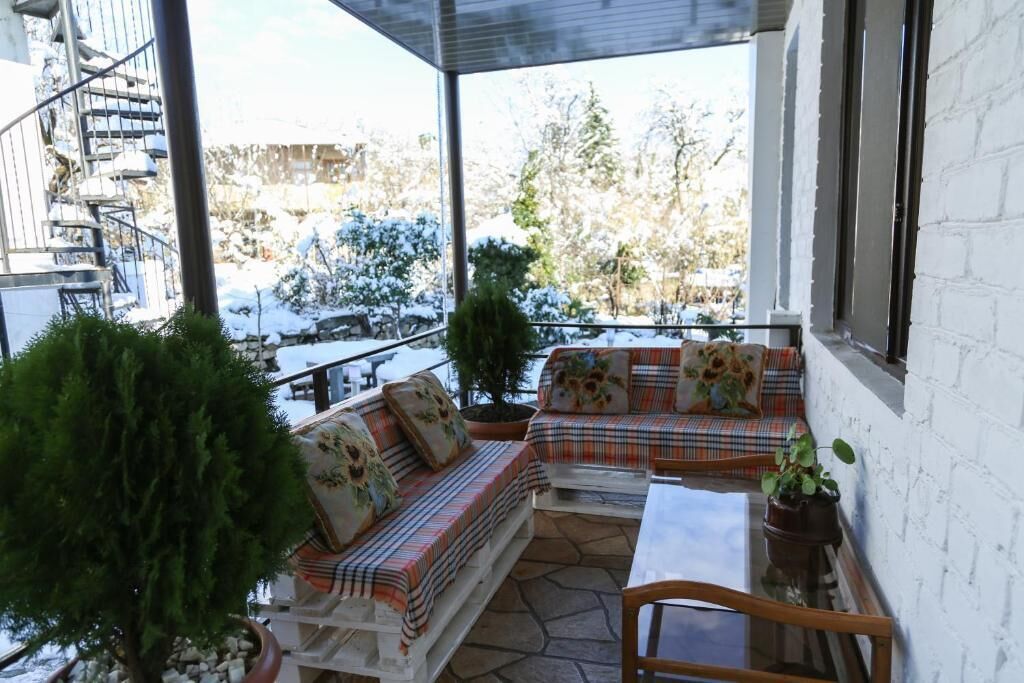 Un espace extérieur abrité, doté d’un sol en pierre, de murs blancs et offrant une vue sur un paysage enneigé.