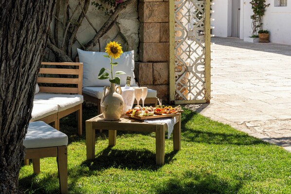 Juego de banco y mesa de madera al aire libre con un girasol, un florero y una bandeja de comida.