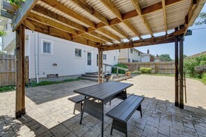 Relax in a serene patio area with a pergola, picnic table, and benches, surrounded by lush greenery.