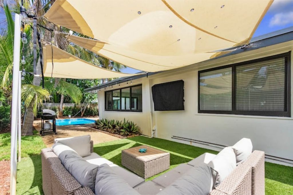 A patio area with outdoor furniture, a swimming pool, and a covered seating area.