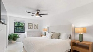 A bedroom with a bed, bedside tables, a ceiling fan, a window, and a potted plant. - Tropical Beach House - Pool & Private Backyard - Close to everything (Boynton Beach)