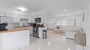 A modern kitchen with white cabinetry, a central island, and a built-in microwave. - Tropical Beach House - Pool & Private Backyard - Close to everything (Boynton Beach)