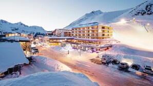 Un complejo turístico en la montaña cubierto de nieve, con un hotel iluminado y un telesilla.