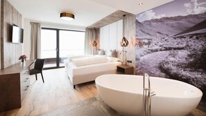 Un dormitorio moderno con una cama grande, una bañera, un escritorio y un televisor.