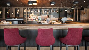 Zona de bar con techo de madera, sillas tapizadas en rojo y una barra con una caja registradora.