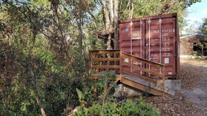 A wooden structure with a metal railing, surrounded by dense foliage. - Logement Atypique (Le diamant)