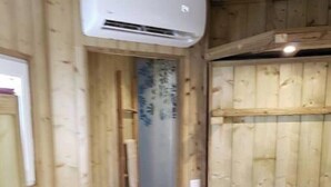 A narrow wooden hallway with a wooden door and an air conditioning unit mounted on the wall. - Logement Atypique (Le diamant)
