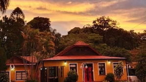 Un bâtiment à deux étages, doté d’un toit rouge et de nombreuses fenêtres, entouré d’arbres et d’une zone herbeuse.